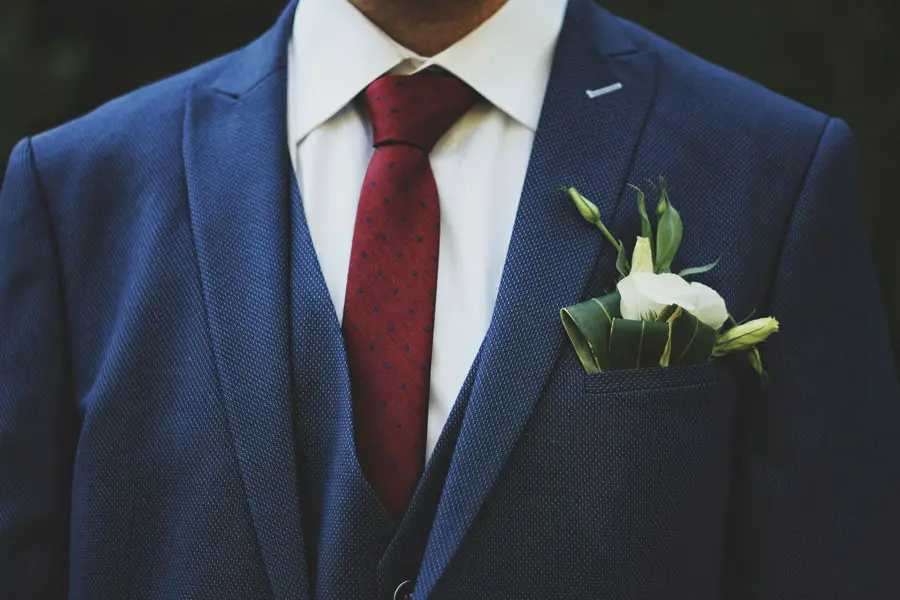 tailor adjusting a man’s suit jacket during a fitting in Manchester